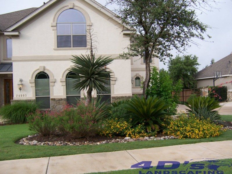 A large white house with a landscaping company logo on the sidewalk