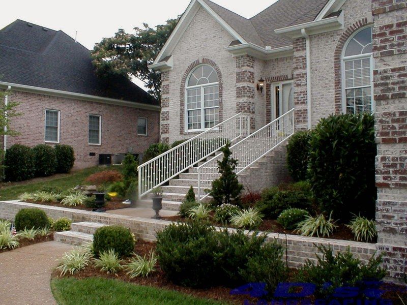 A brick house with a white railing and stairs