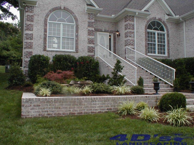 A white brick house with a white railing and stairs
