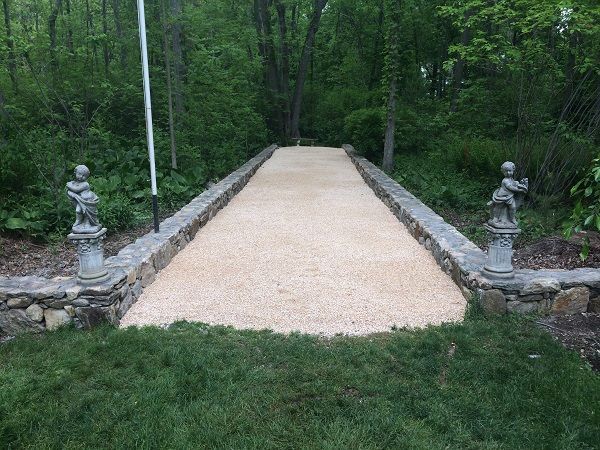 A stone walkway leading to a lush green forest.