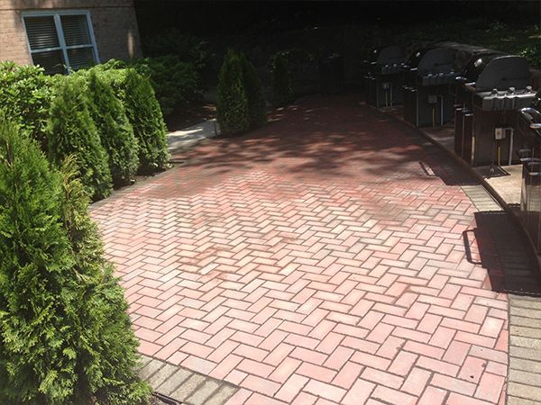 A brick walkway with a grill in the background