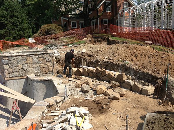 A man is working on a stone wall in a construction site.