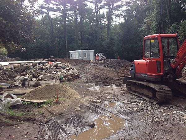 A red excavator is sitting in the middle of a muddy field.