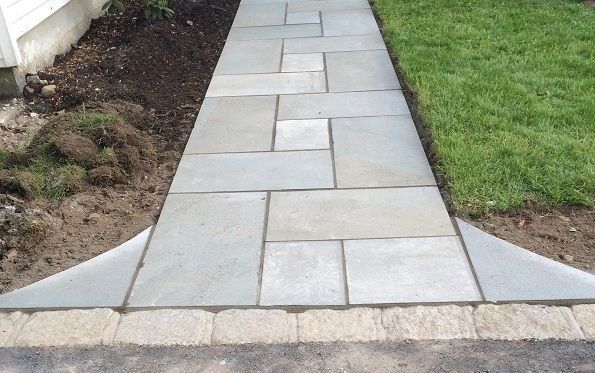 A stone walkway is being built in front of a house