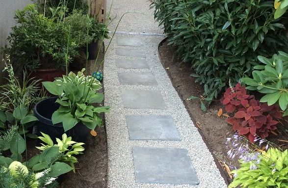 A stone walkway in a garden surrounded by potted plants