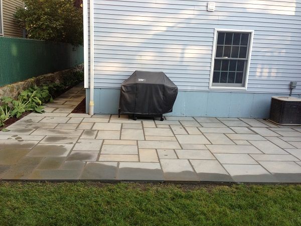 A patio with a grill on it in front of a house.