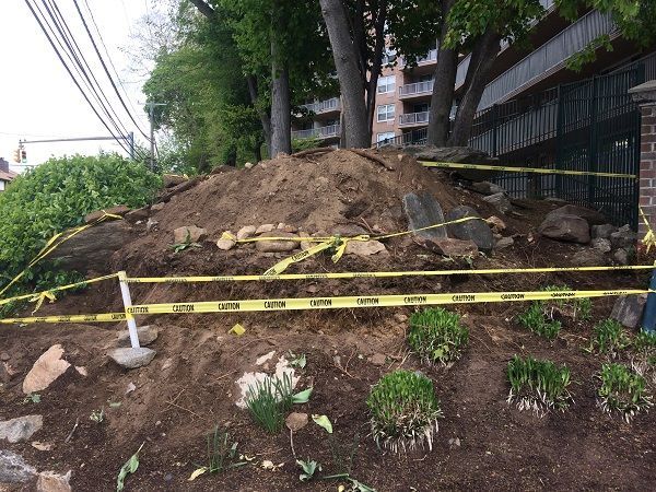 A large pile of dirt is surrounded by yellow tape