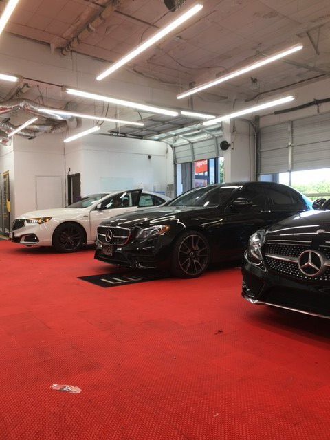 A row of cars are parked in a showroom with a red carpet