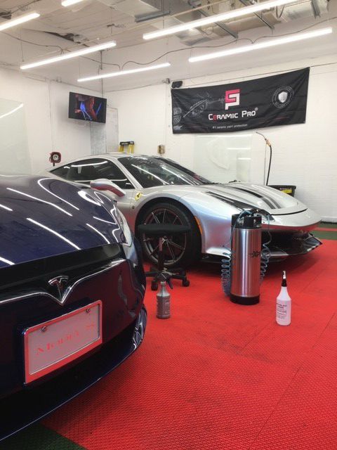 A tesla model s is parked next to a silver sports car