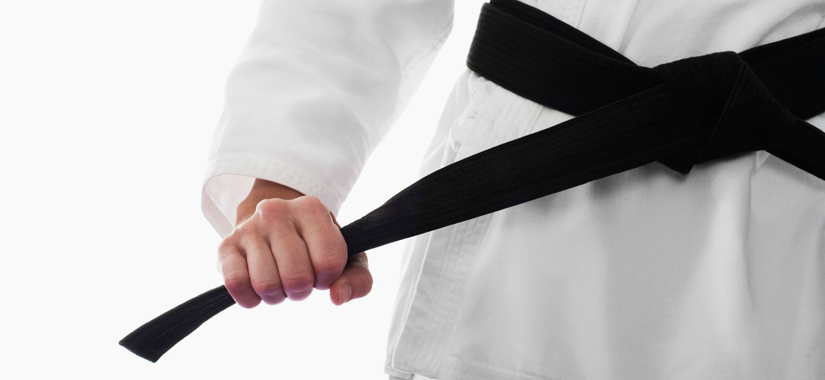 Man in white karate uniform demonstrating an arm lock on another man in a martial arts class.