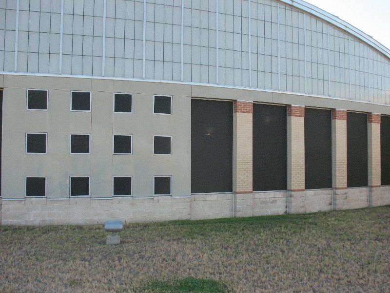 The side of a commercial building with small square windows on the left and tall, rectangular windows on the right.