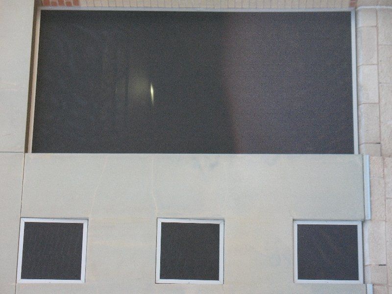 A wall with a large dark rectangular window at the top and three smaller square windows arranged in a row below.