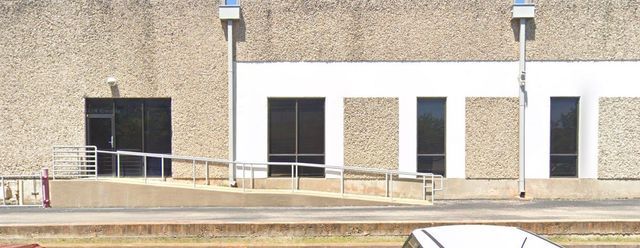 A concrete exterior of a building featuring a long ADA-compliant wheelchair ramp leading to an entrance door.