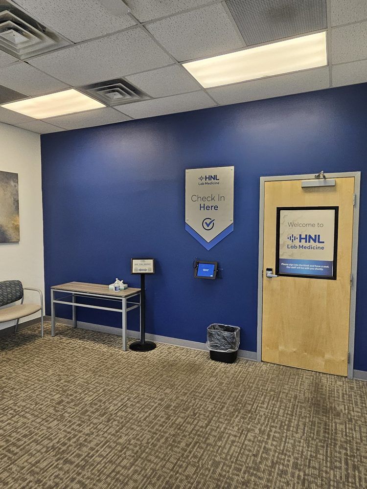 Blue-walled office entryway with a door, sign, table, and small screen.