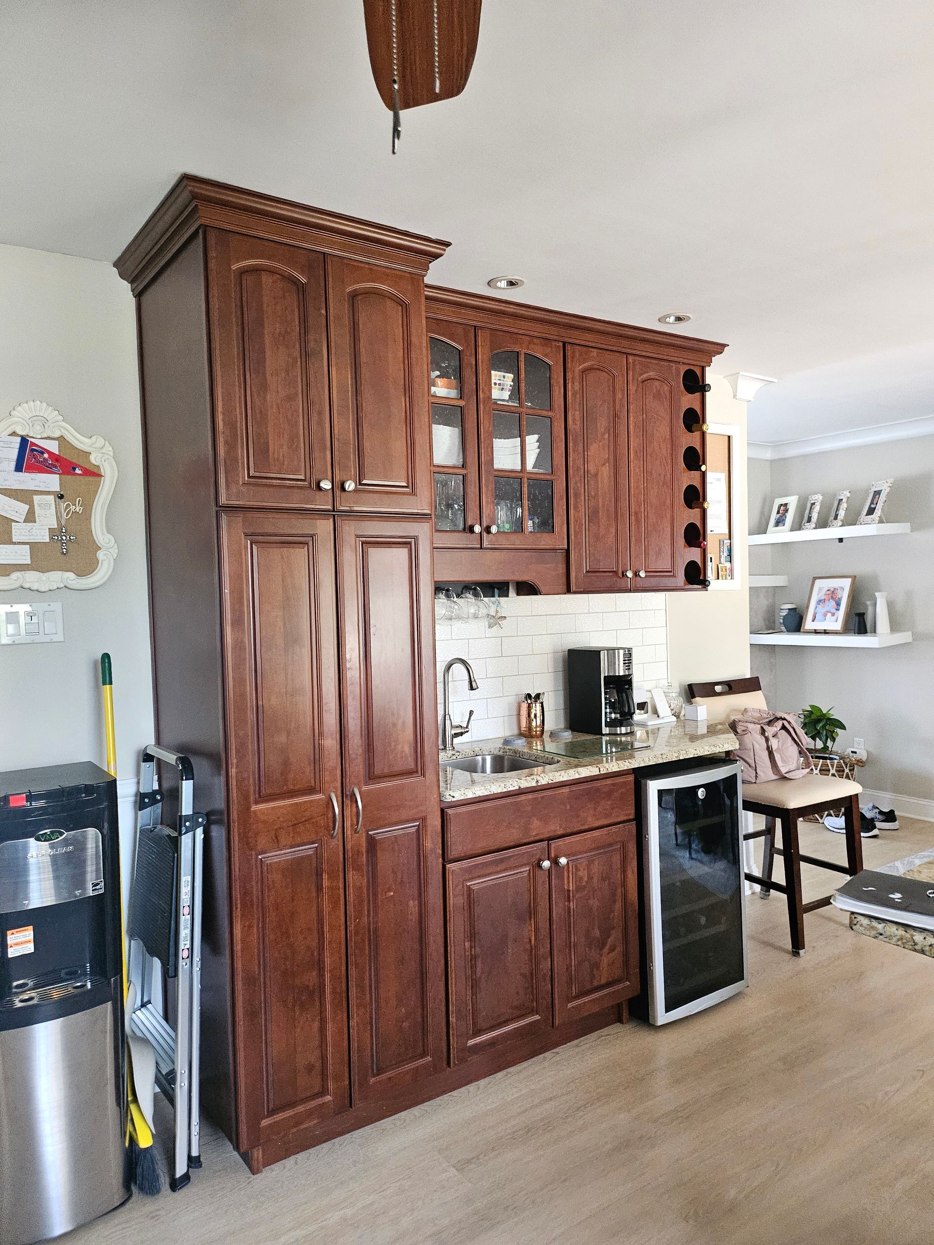 Wooden kitchen cabinets with countertop, stainless trash can, and a small bar area in a bright room.