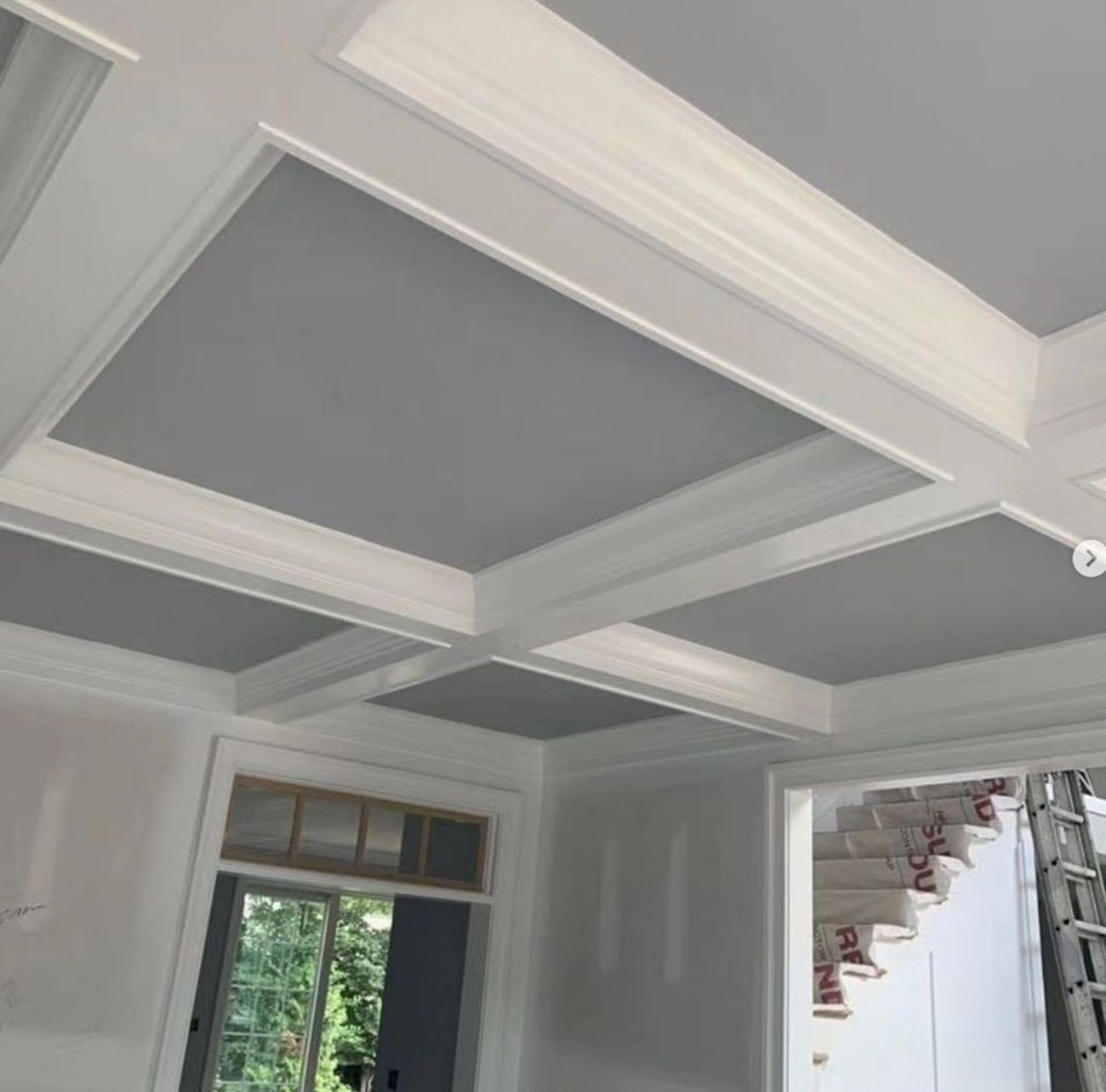 White coffered ceiling with recessed panels in a bright room under construction