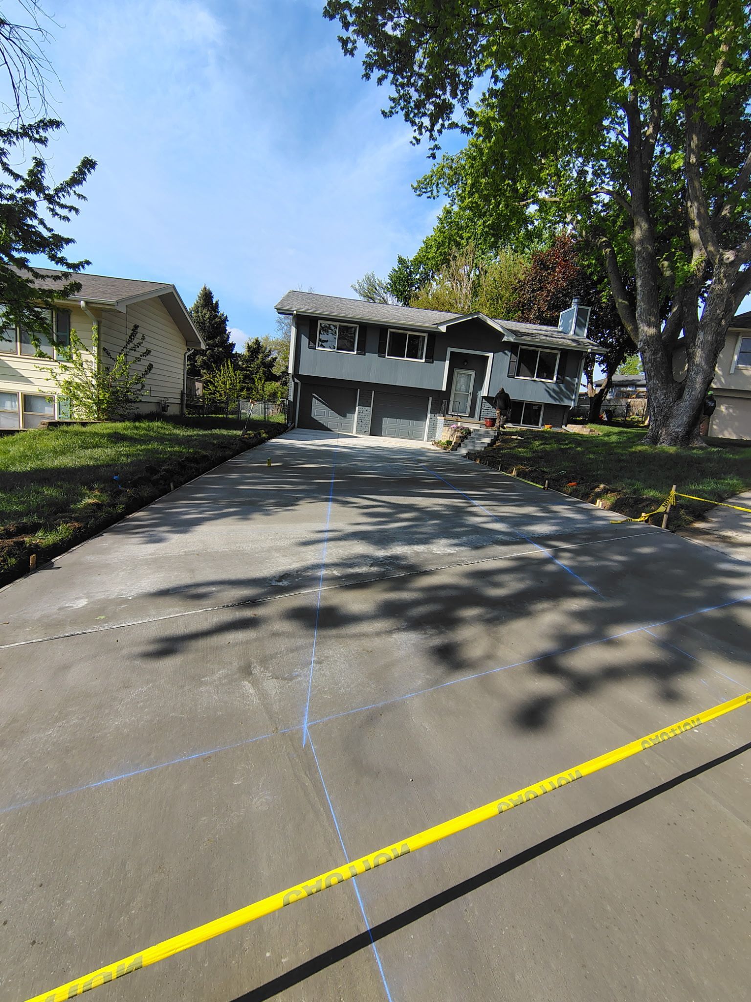 Wide driveway leading to a two-story house with trees and bright sunlight