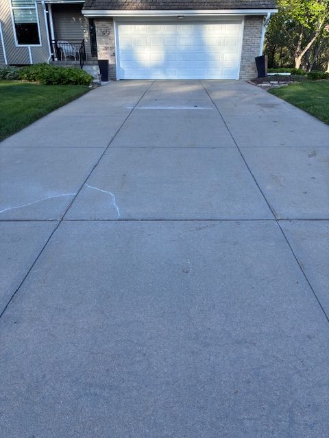 Concrete driveway leading to a white garage with a small crack in the pavement.