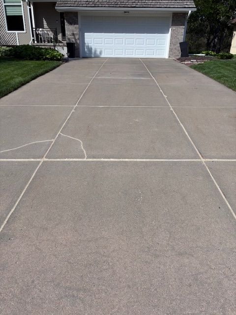 Cracked concrete driveway leading to a white garage door in a suburban home