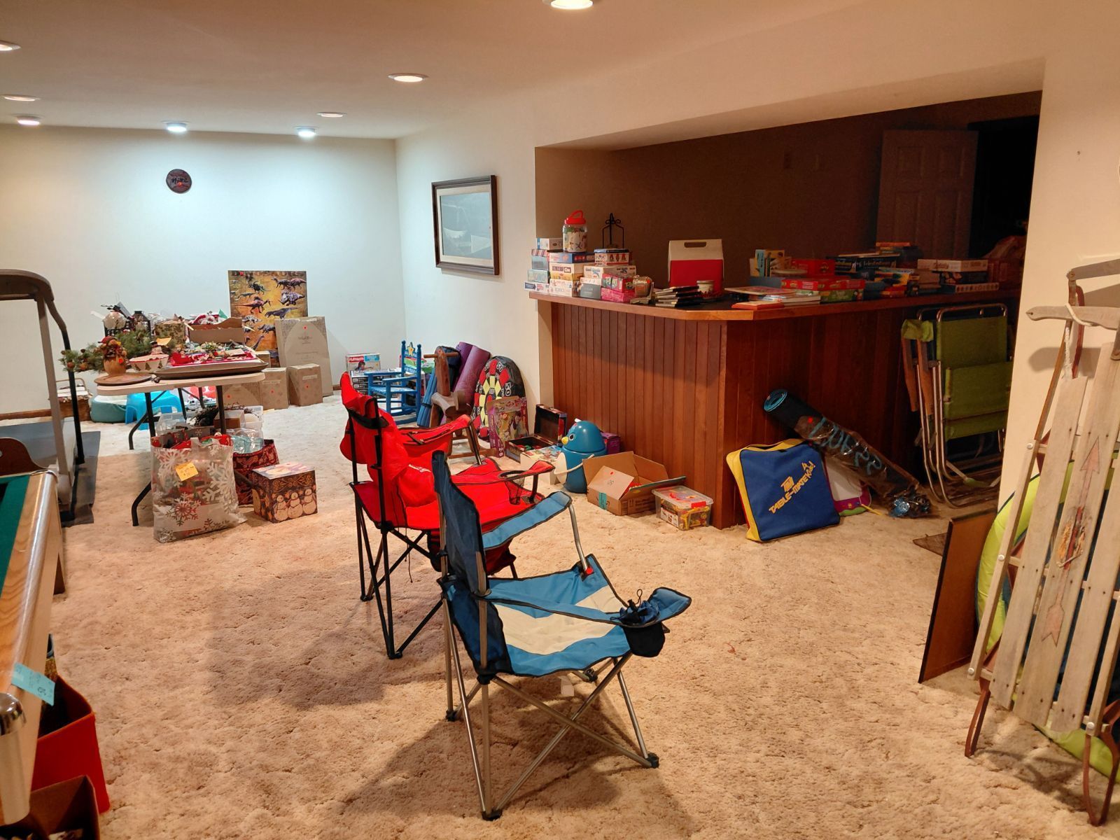 A cluttered basement with furniture, sports equipment, and various items spread across the floor.