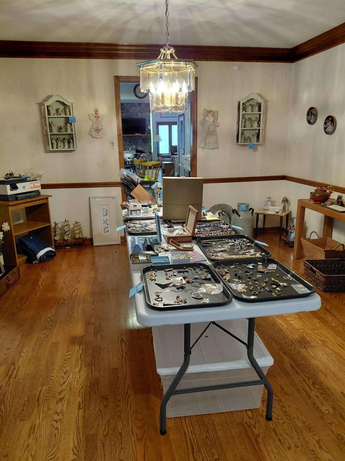 A room with a table displaying jewelry and other objects; a chandelier hangs above.