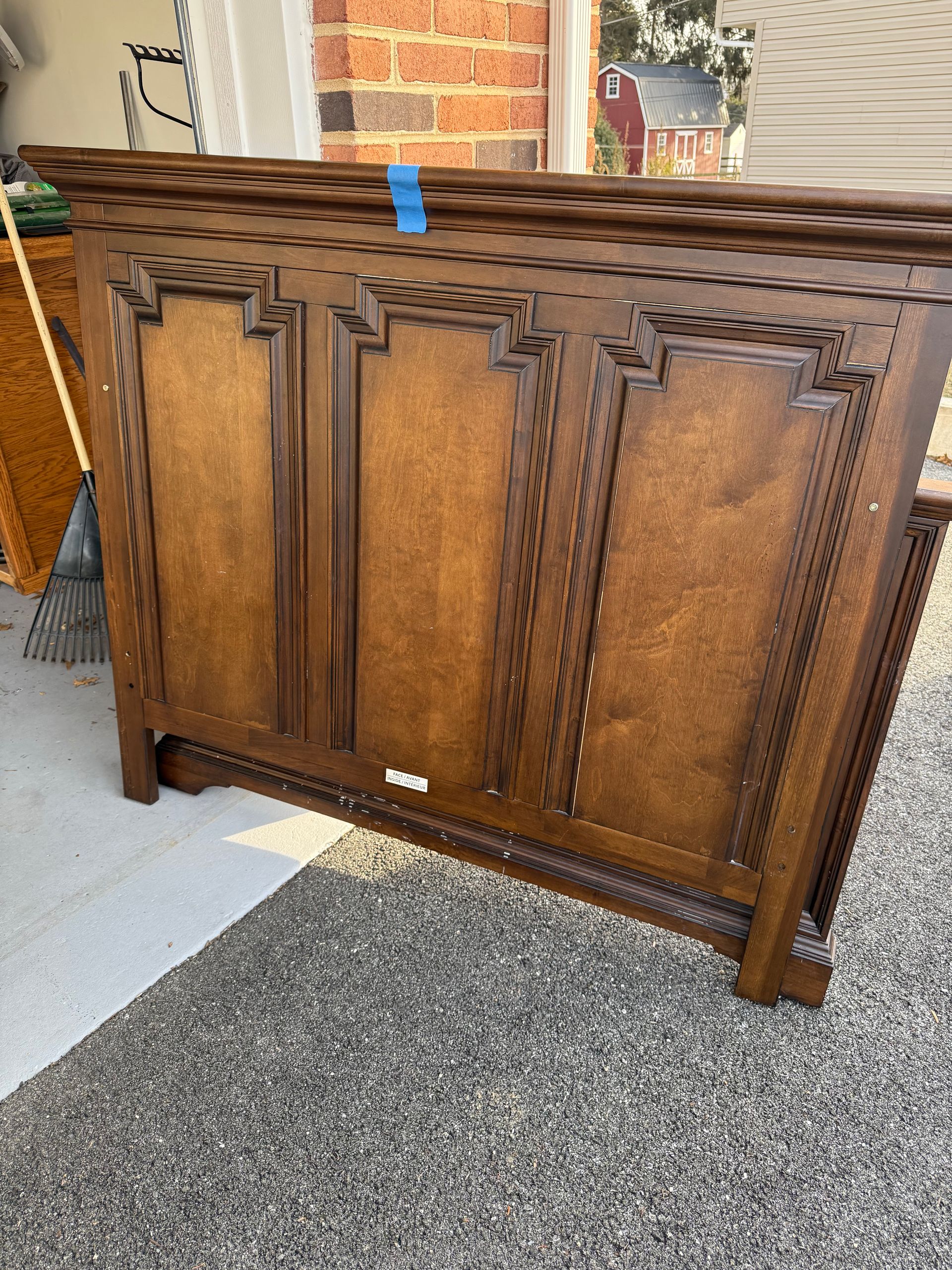 A wooden cabinet is sitting on the ground in a garage.