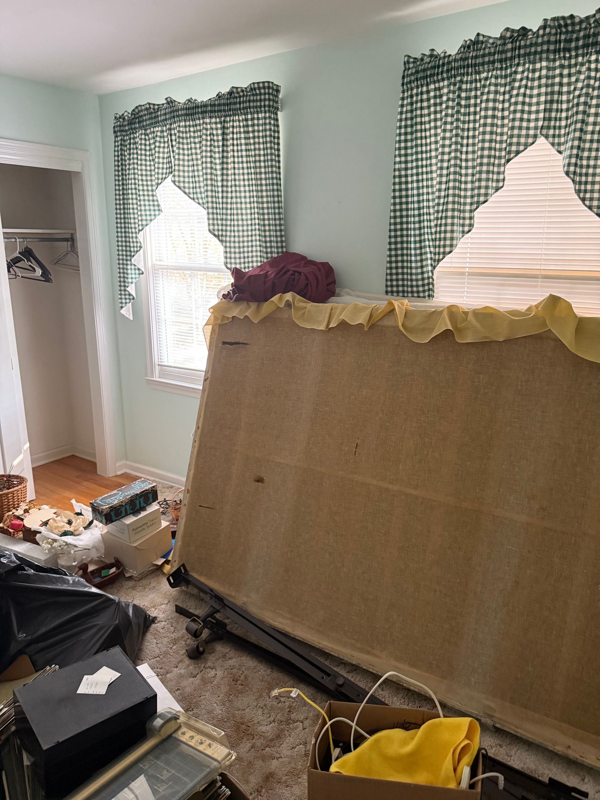 A messy room with a bed and a box on the floor.