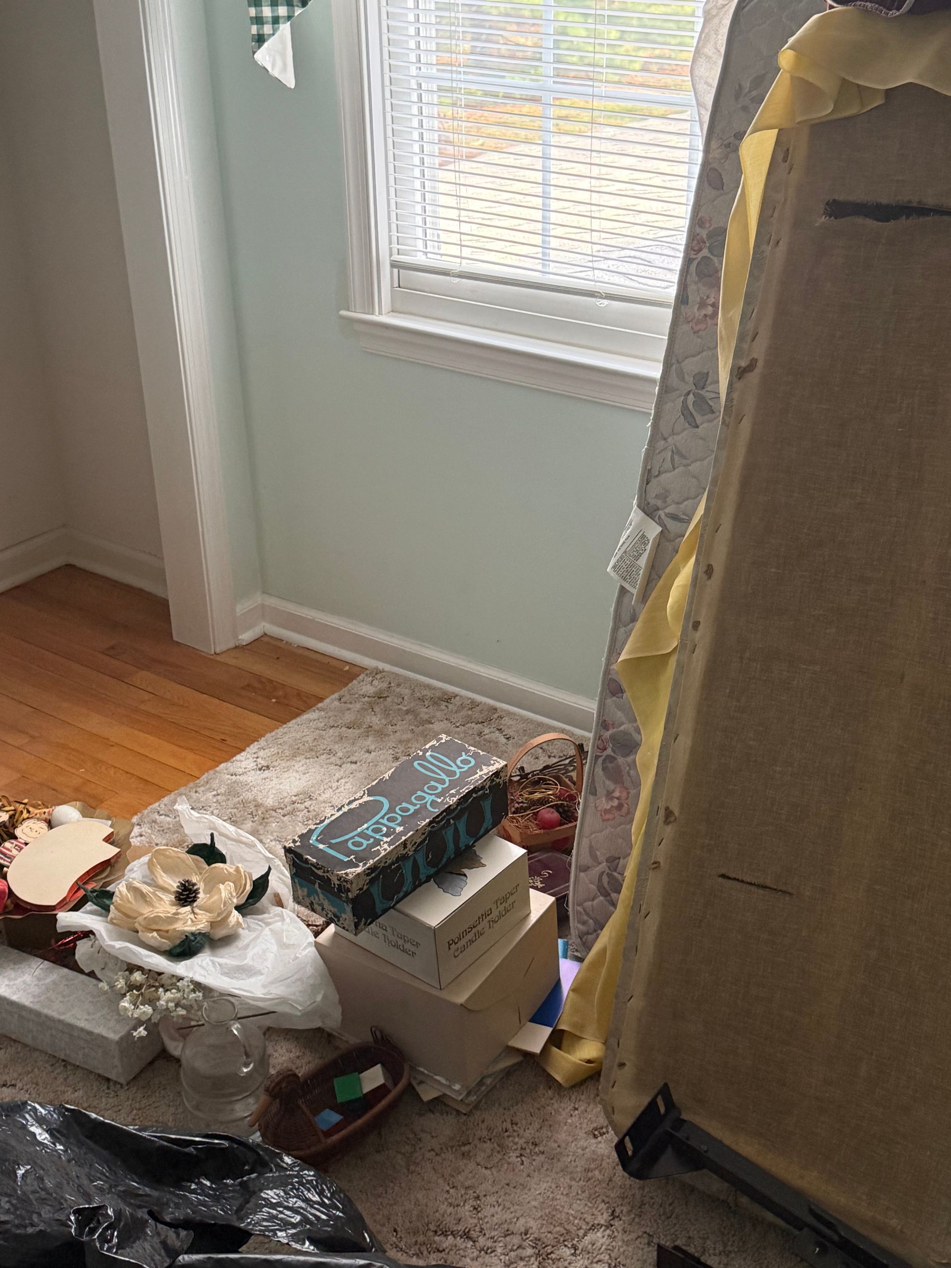 A room with a stack of boxes on the floor and a window.