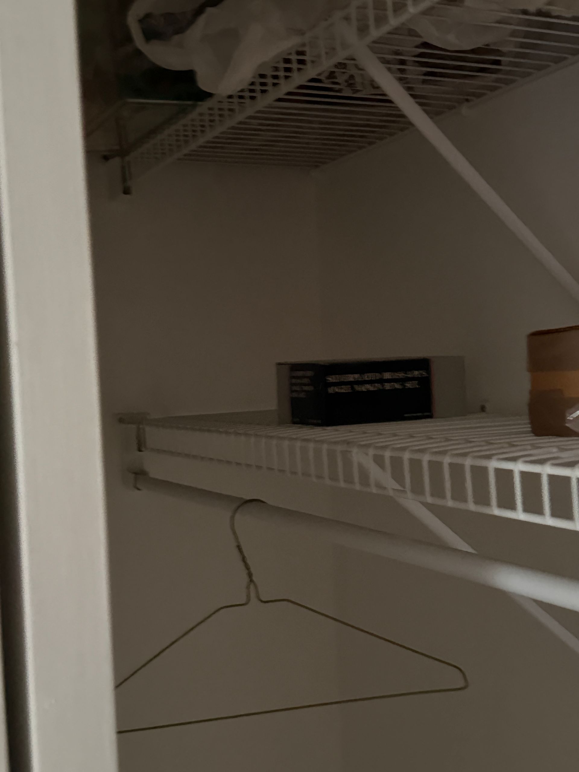A closet with a wire shelf and a hanger