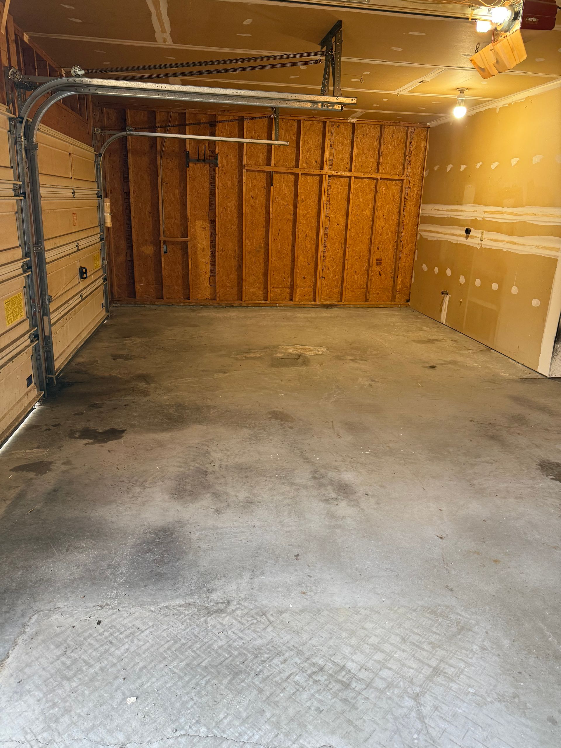 An empty garage with a garage door open and a ceiling fan.
