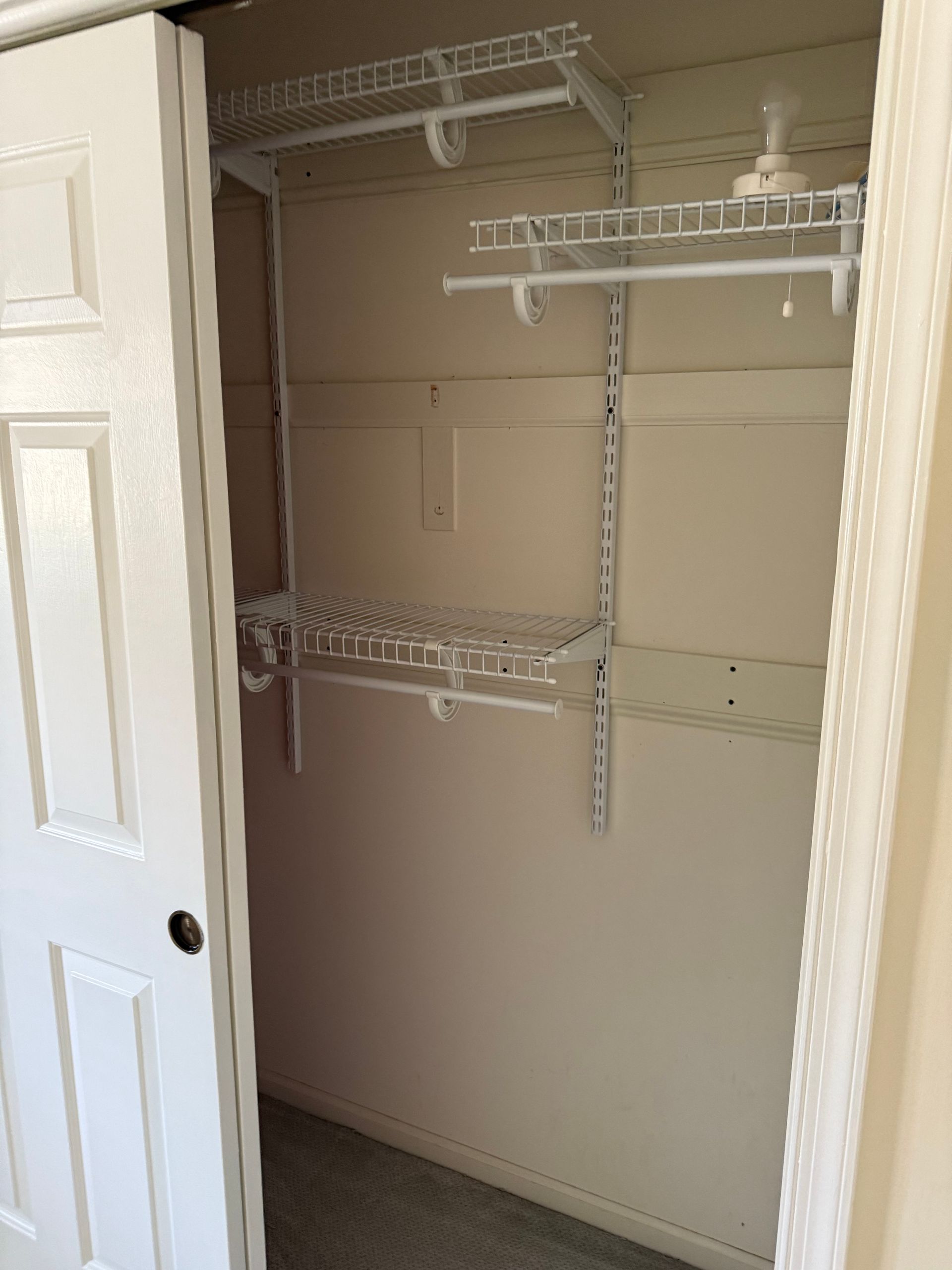 An empty closet with a white door and shelves.