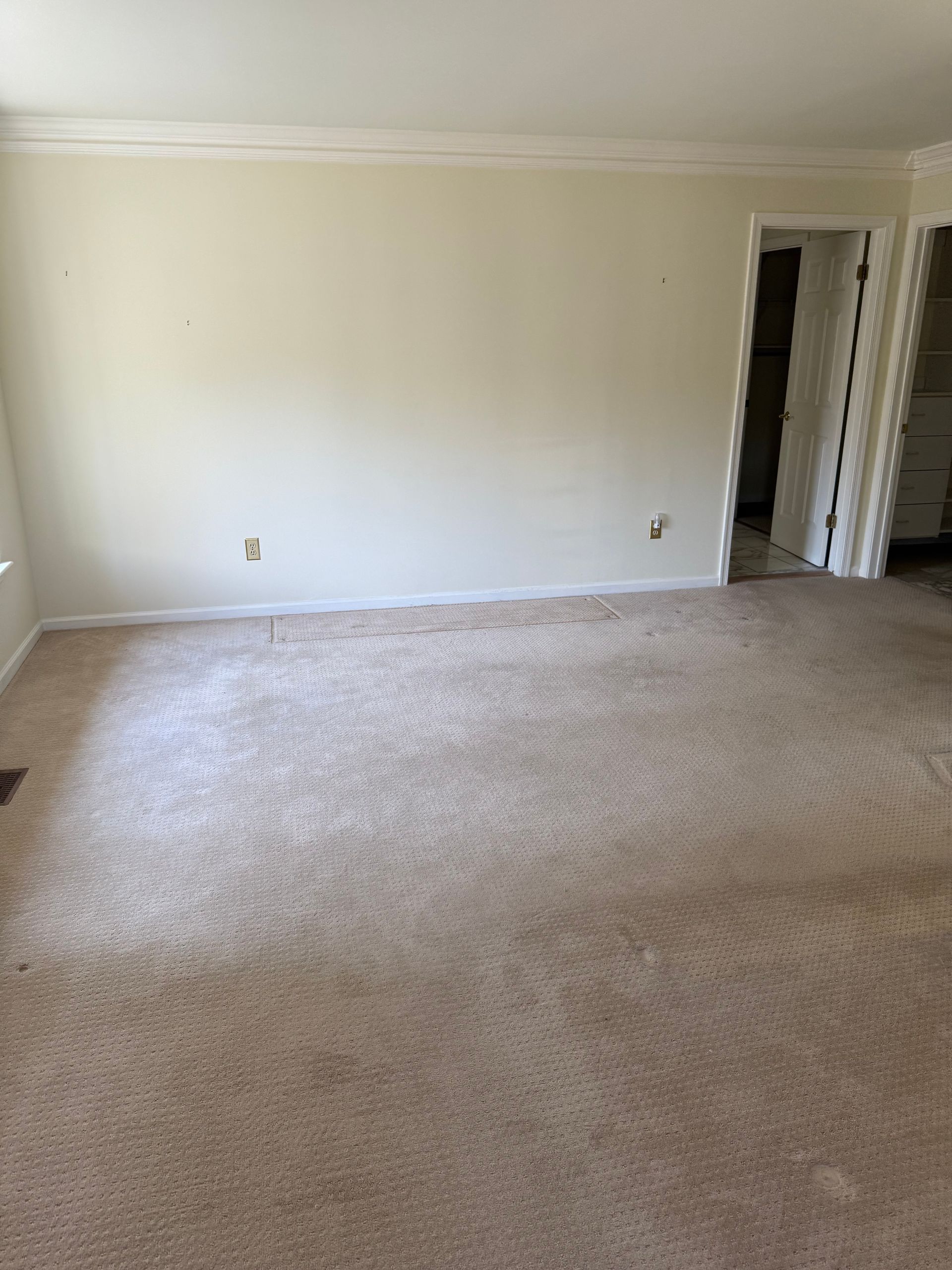 An empty living room with a carpeted floor and white walls.