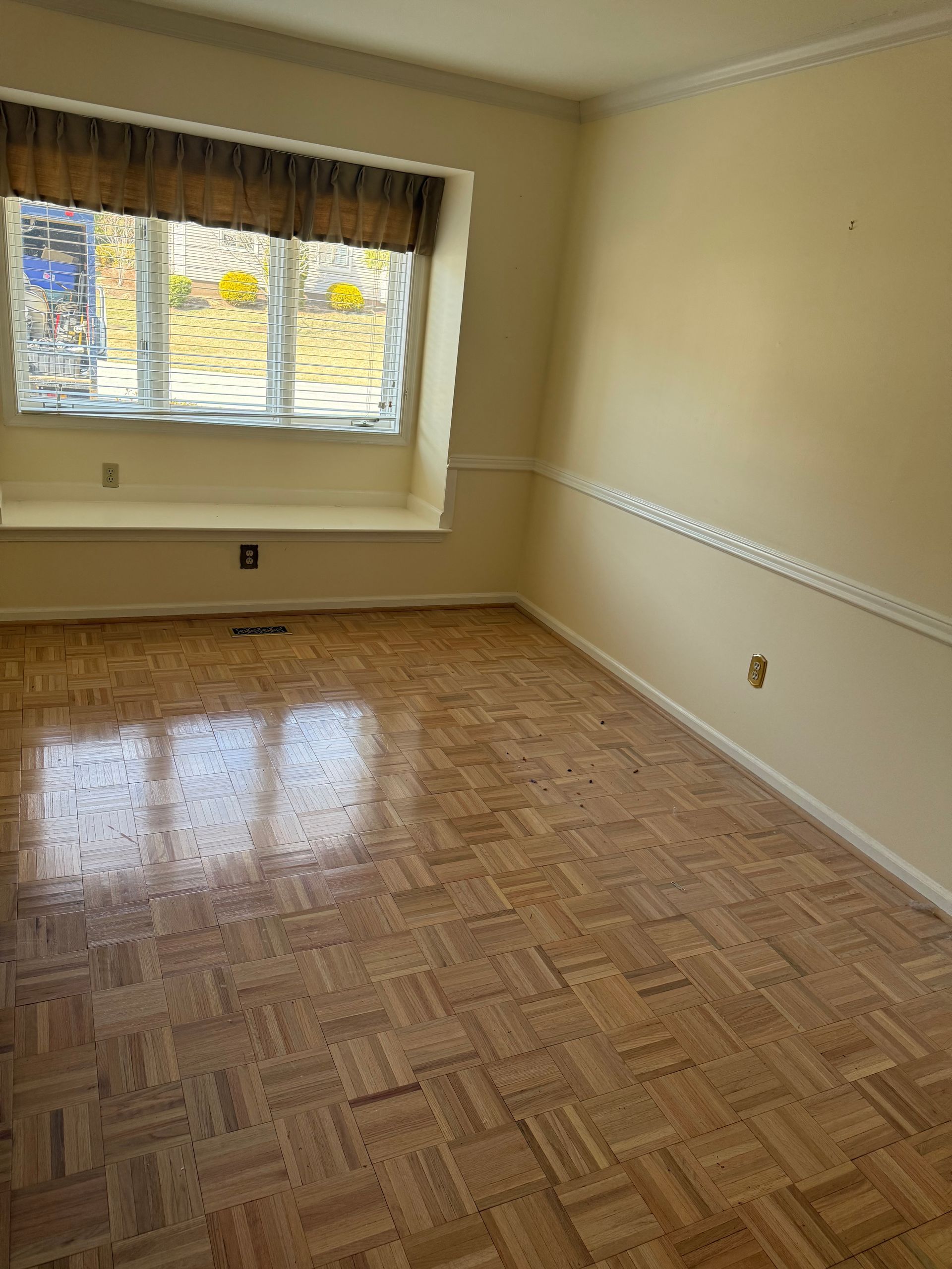 An empty living room with a wooden floor and a window.