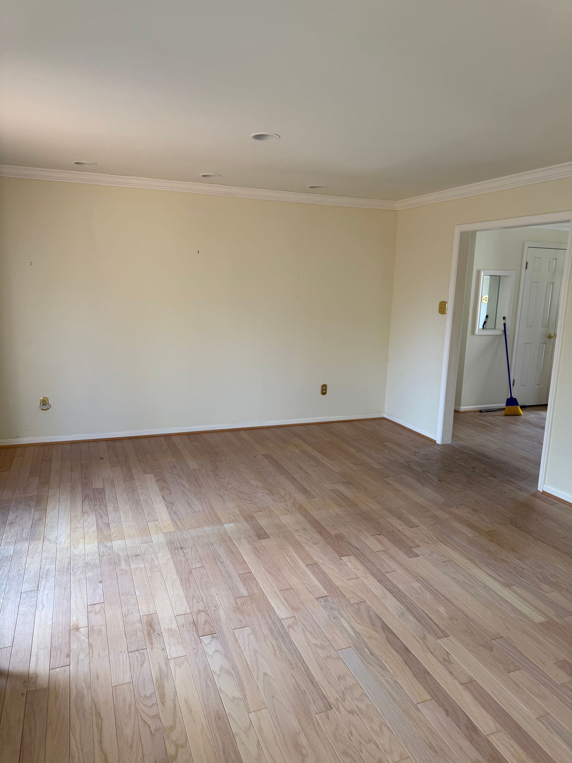 An empty living room with hardwood floors and white walls.