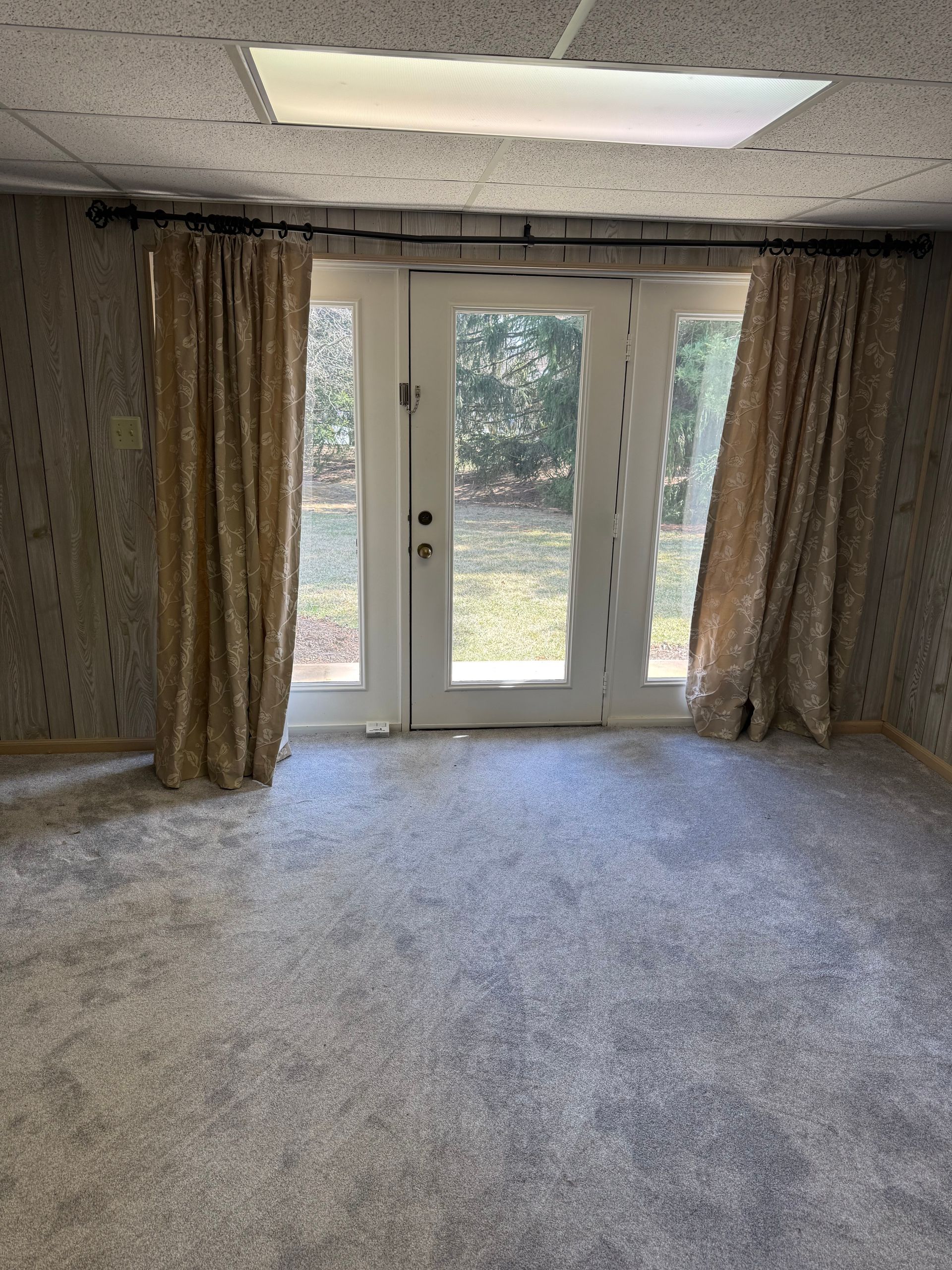 An empty room with a sliding glass door and curtains