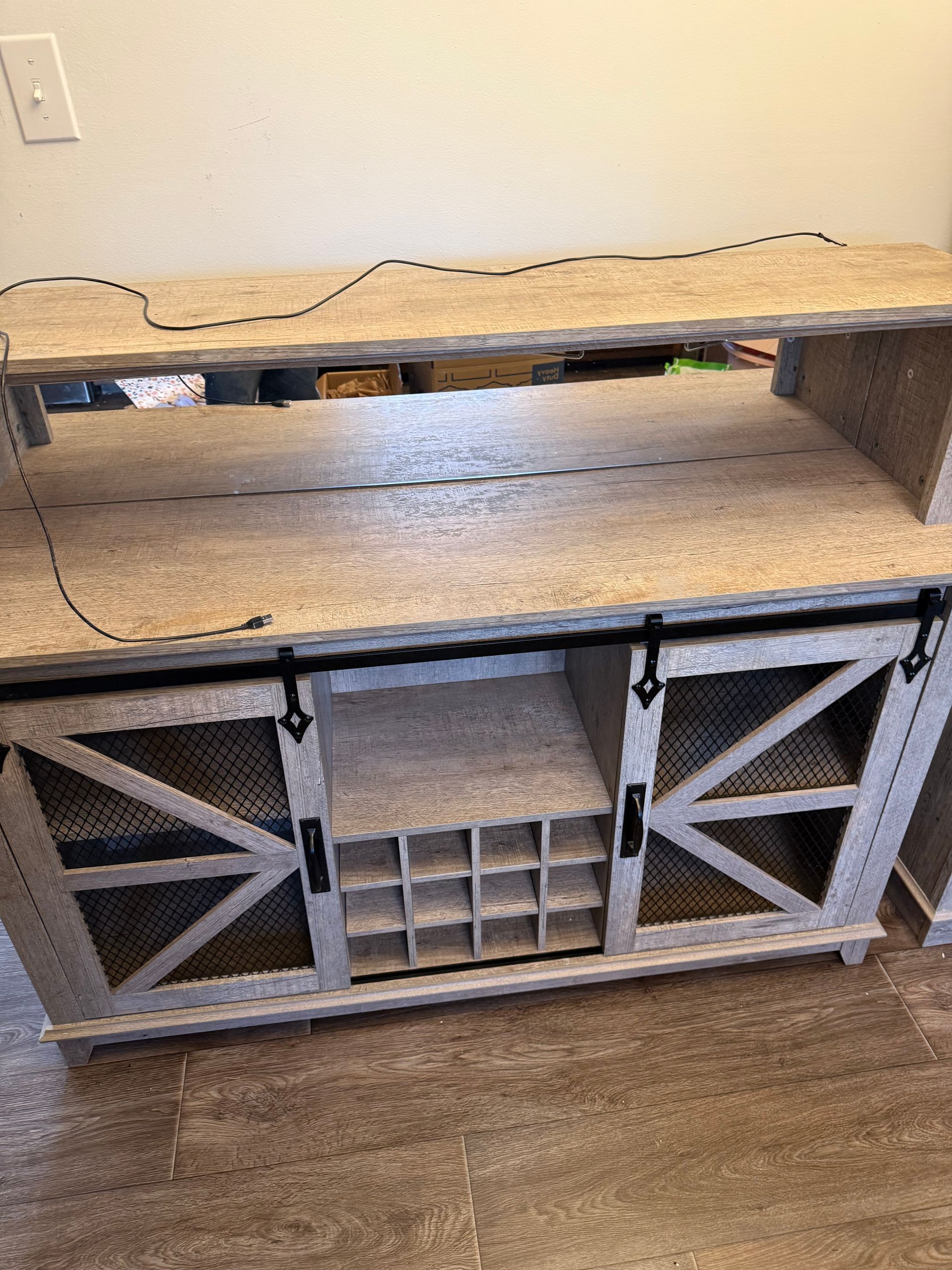 A wooden shelf with a wine rack underneath it is sitting on a wooden floor.