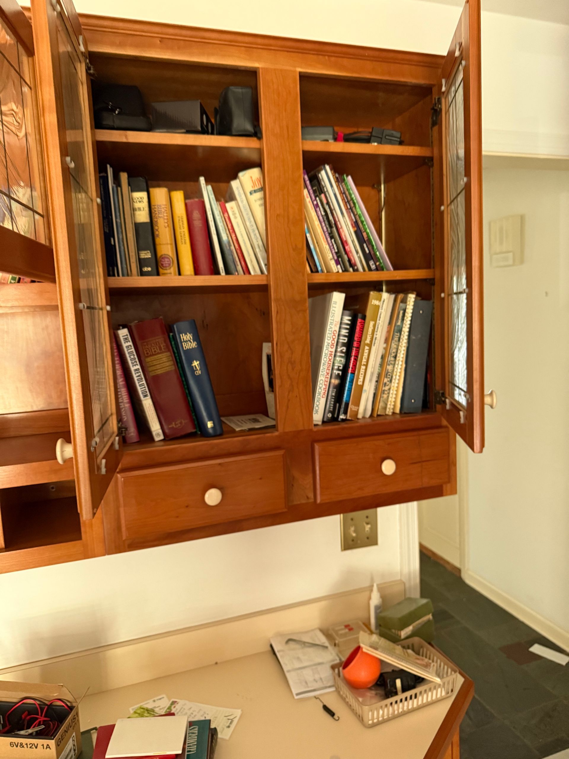 A bookcase with a glass door and drawers filled with books