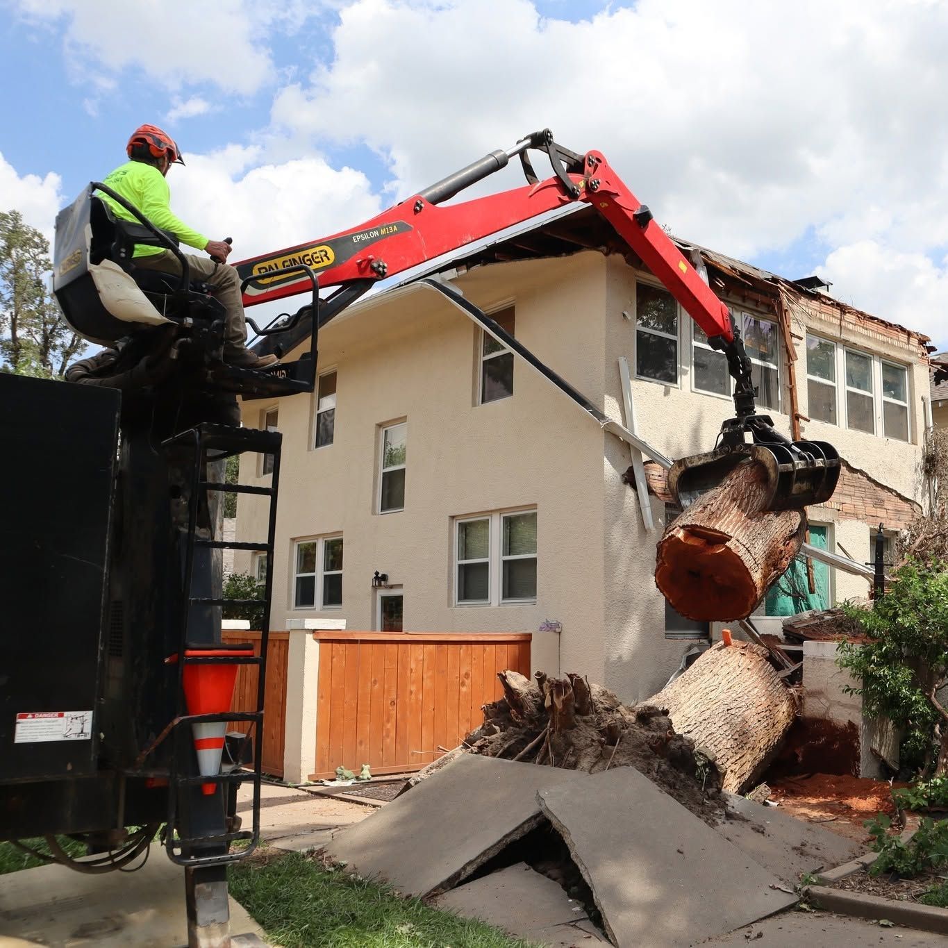 Worker on excavator demolishing a house, with rubble and broken concrete in front