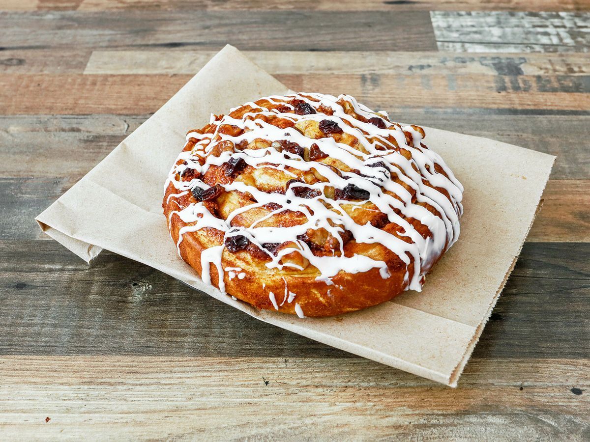 A pastry is sitting on a napkin on a wooden table.