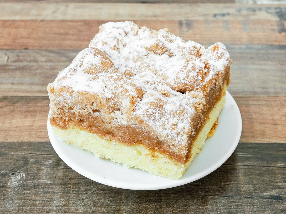 A piece of cake on a white plate on a wooden table.