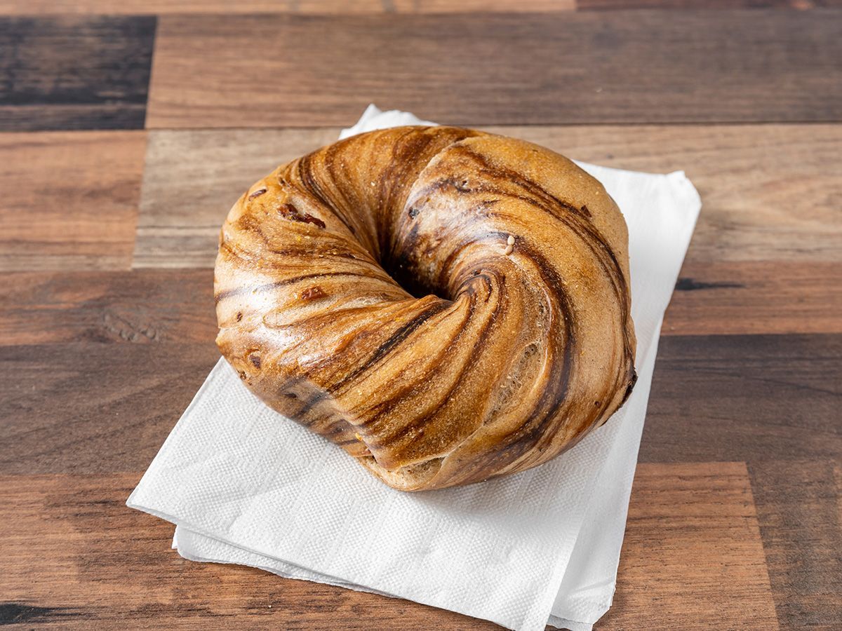 A donut is sitting on a napkin on a wooden table.