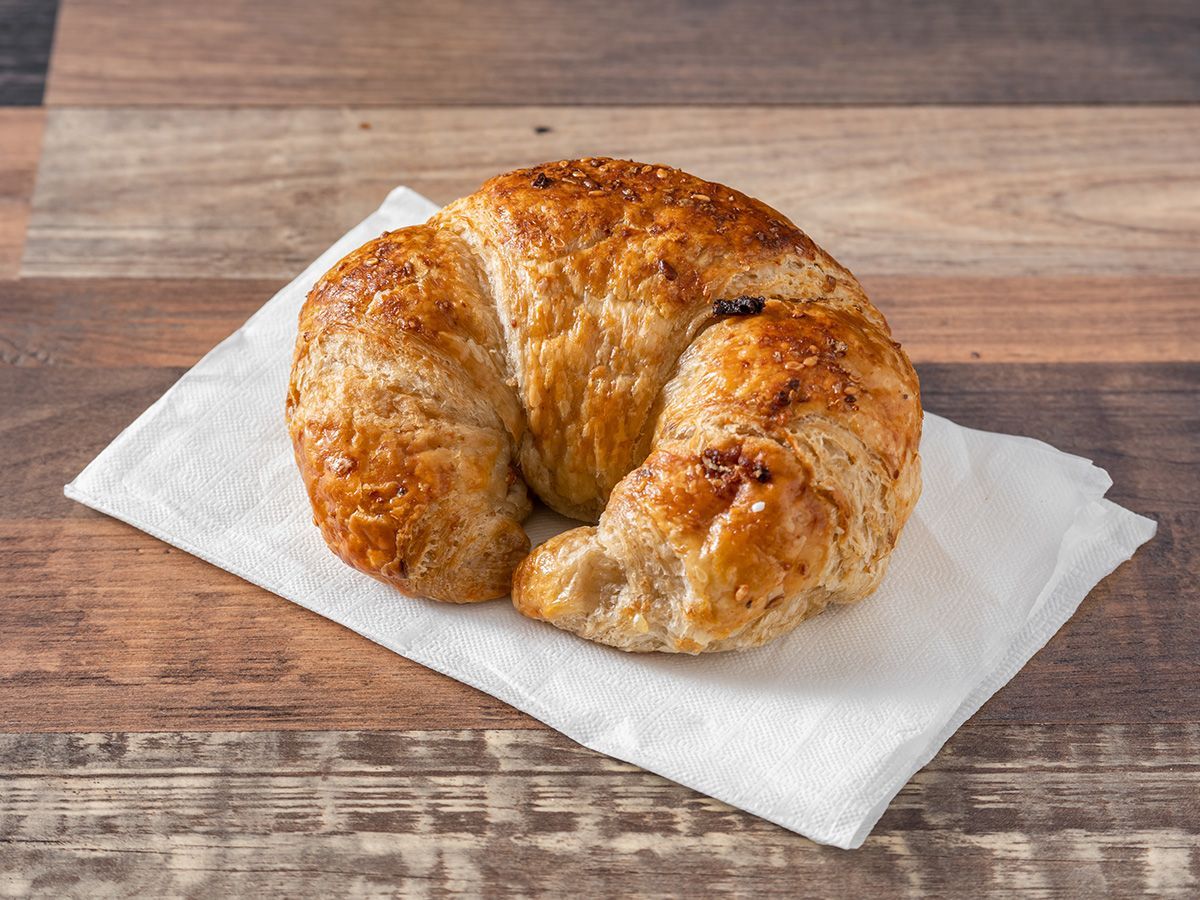 A croissant is sitting on a napkin on a wooden table.