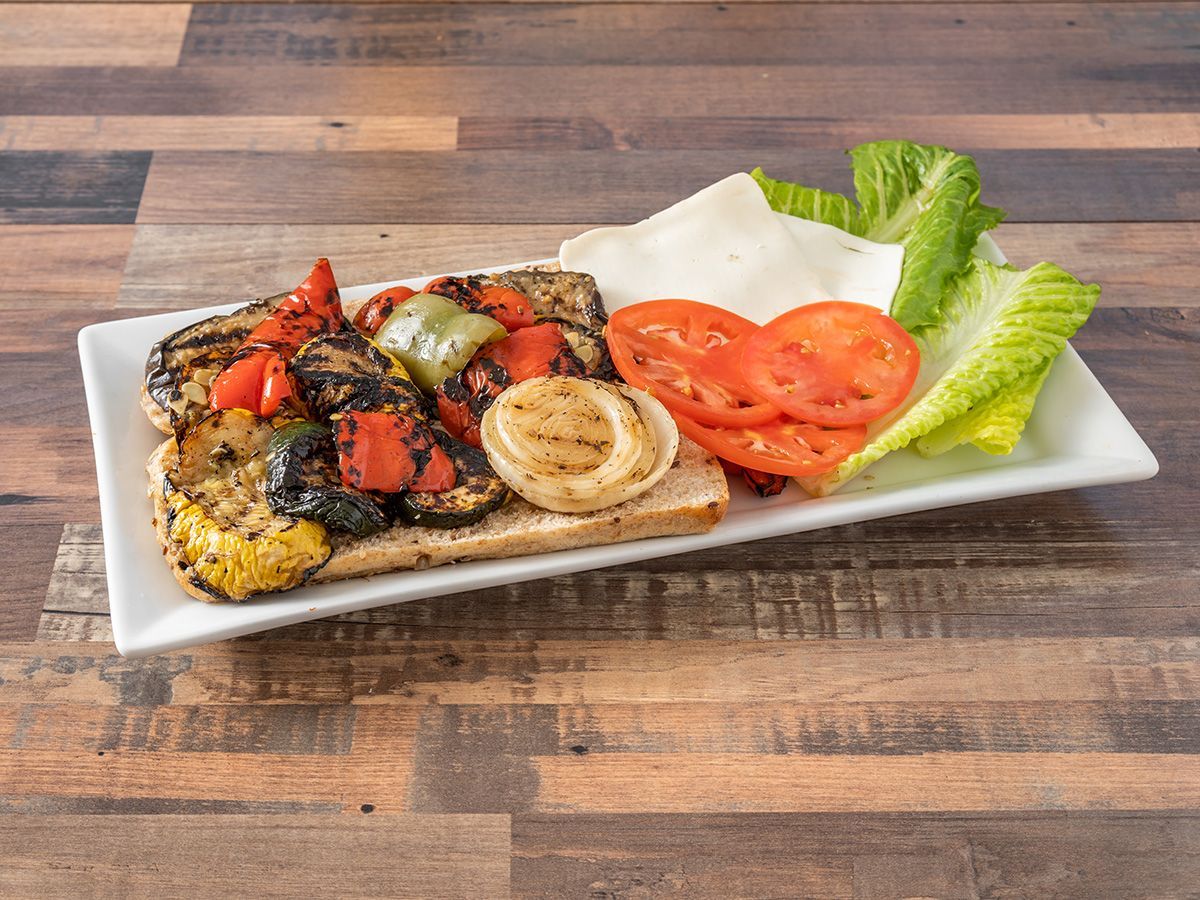 A white plate topped with grilled vegetables and cheese on a wooden table.
