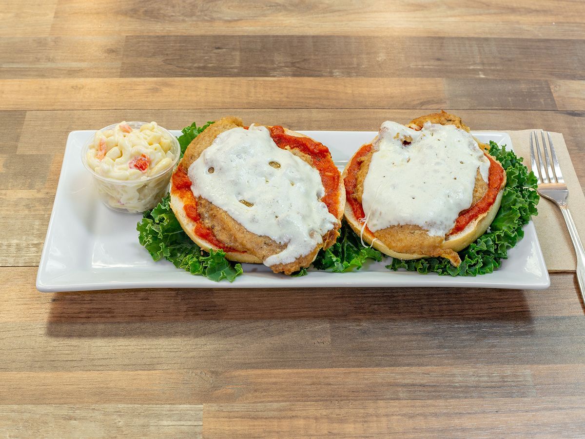 A white plate topped with two chicken sandwiches and coleslaw on a wooden table.
