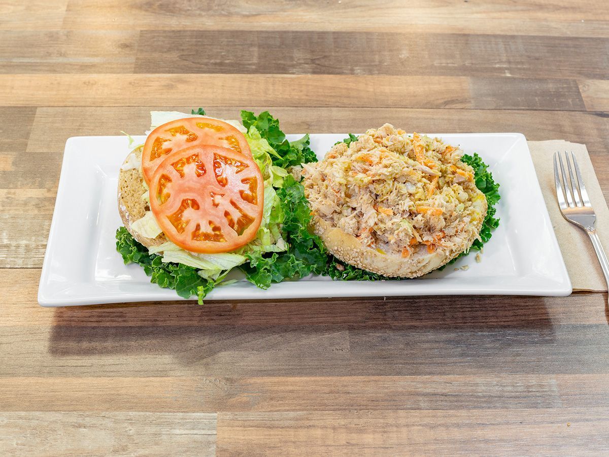 A sandwich with lettuce , tomato and cheese on a plate on a wooden table.