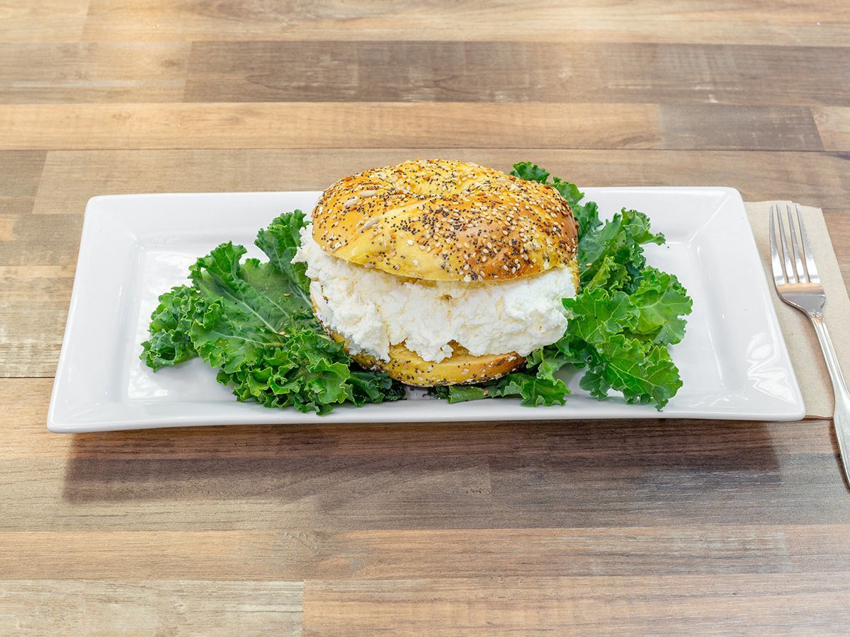 A white plate topped with a sandwich and lettuce on a wooden table.