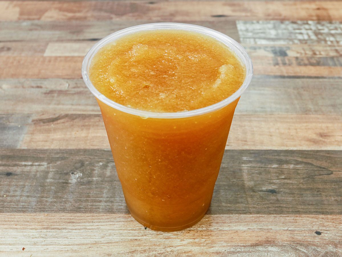 A cup of orange juice is sitting on a wooden table.