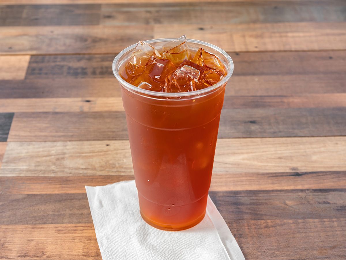 A cup of orange juice is sitting on a wooden table.