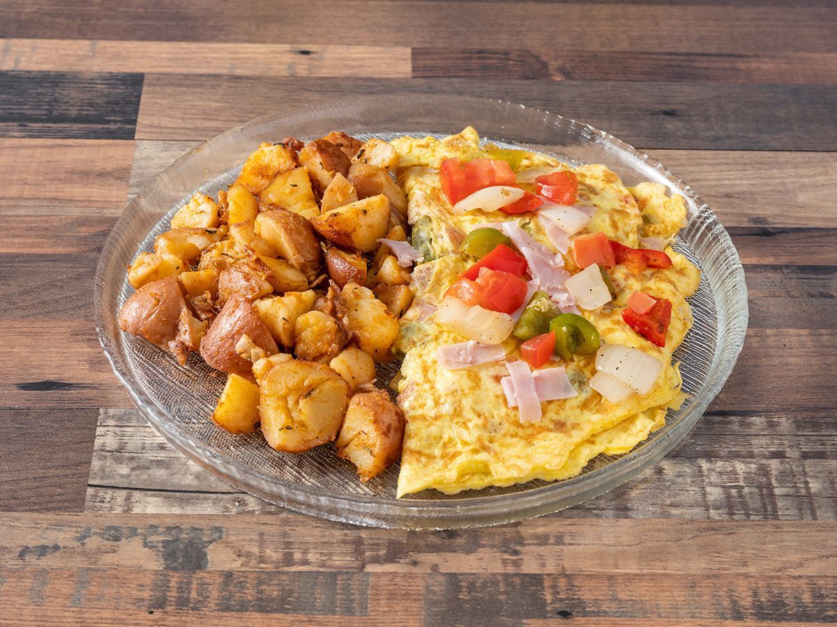 A plate of food with potatoes and an omelet on a wooden table.