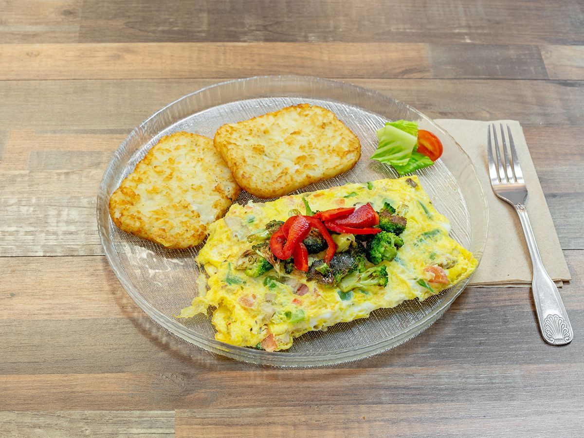A plate of food with hash browns and an omelet on a wooden table.